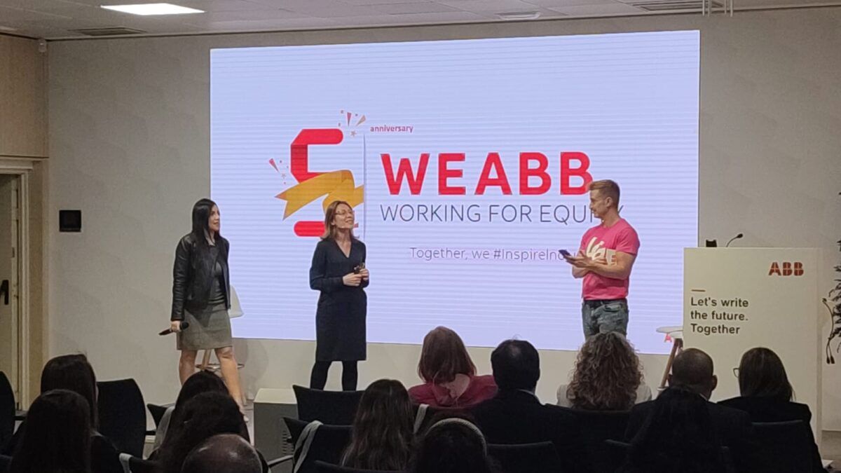 Tres oradores, dos mujeres y un hombre, de pie en un escenario durante un evento corporativo de ABB. Detrás de ellos hay una gran pantalla con el logotipo del quinto aniversario de WEABB y el eslogan de la compañía: 'Let's write the future. Together' (Escribamos el futuro. Juntos).
