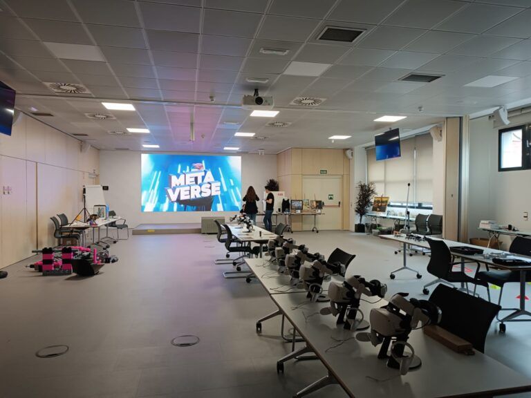 Sala moderna de formación o demostración tecnológica con mesas equipadas con visores de realidad virtual. Actividad de realidad virtual para team building.