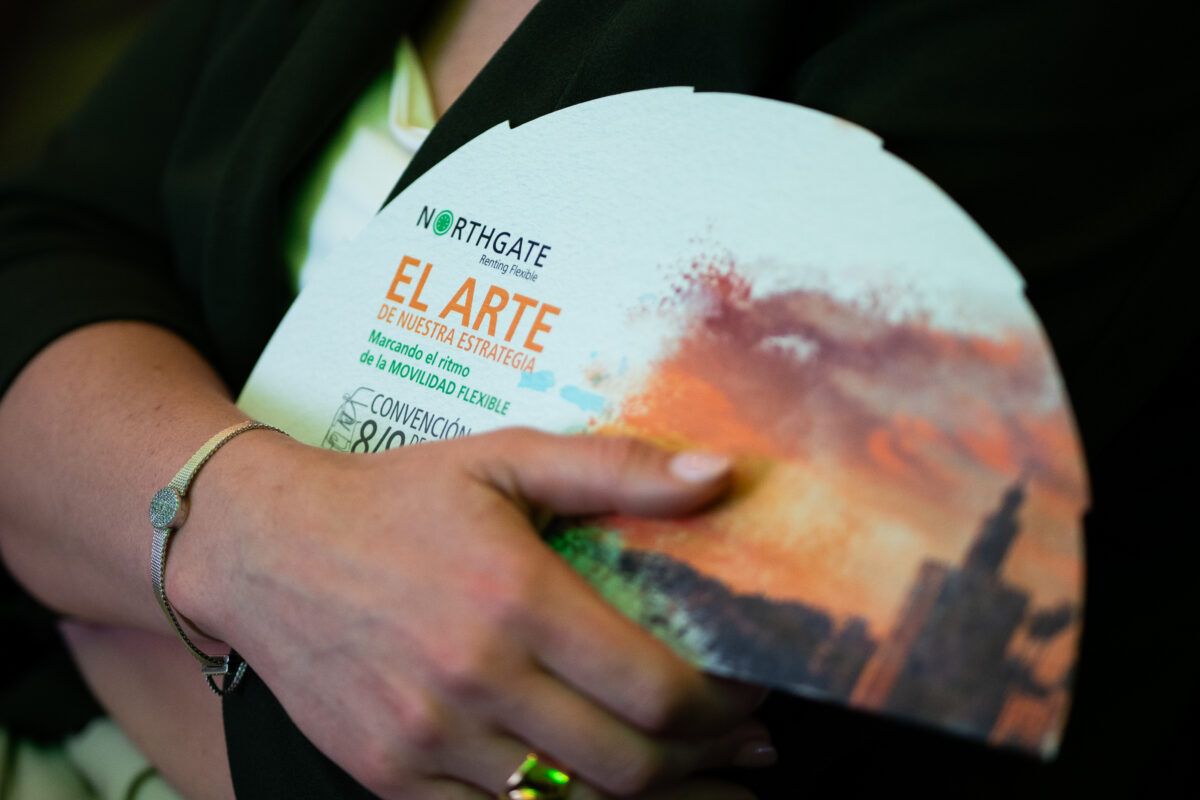 Una persona sostiene un folleto corporativo o díptico blanco con el logotipo de Northgate Renting Flexible y el texto 'EL ARTE DE NUESTRA ESTRATEGIA', con una imagen abstracta en tonos cálidos.
