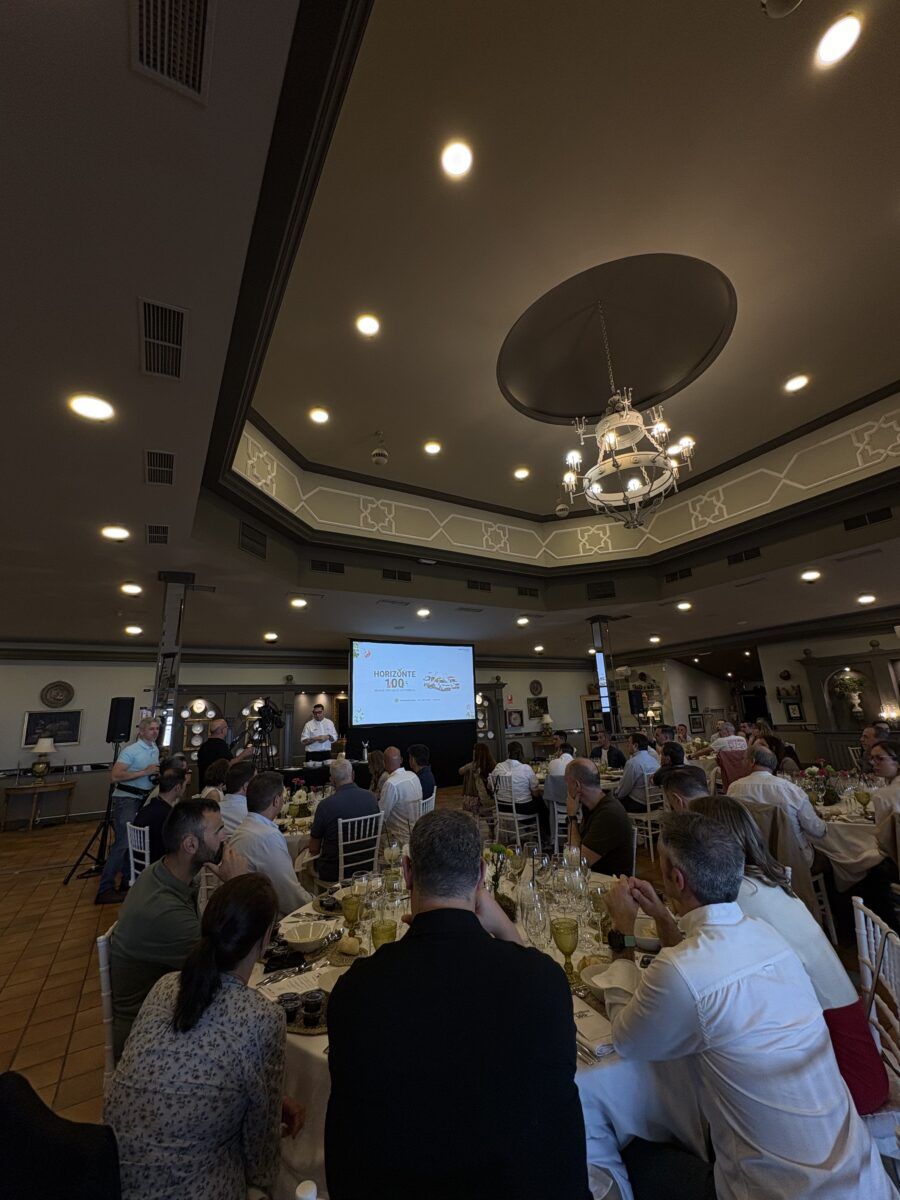 Salón de banquetes lleno de invitados cenando en mesas redondas durante la presentación de la convención corporativa.
