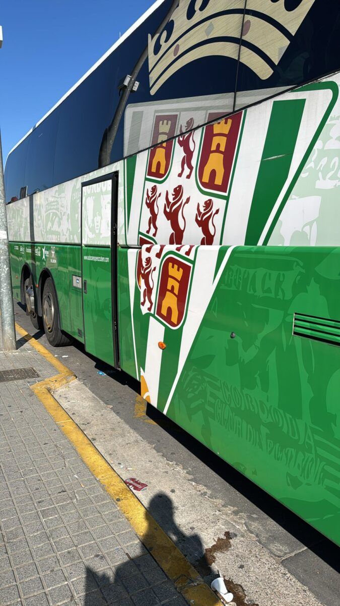 • Lateral de un autobús de pasajeros decorado con un diseño verde y blanco que incluye el escudo de la ciudad de Córdoba.